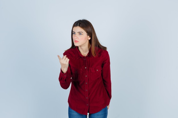 girl in burgundy shirt warning with finger and looking serious.