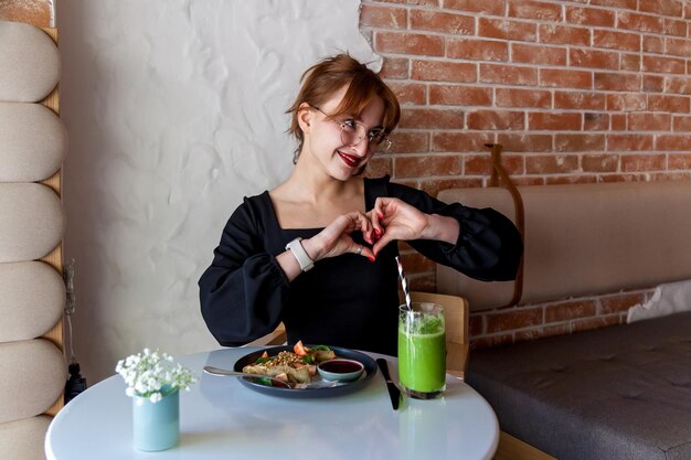 Foto una ragazza in un caffè a colazione mostra vari gesti con le mani