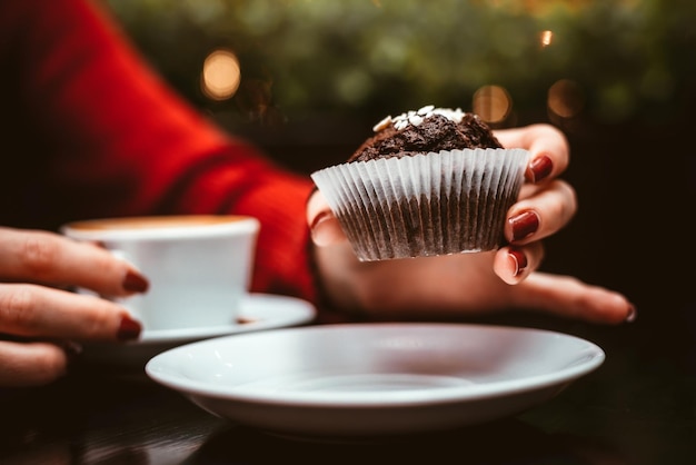 The girl in the cafe eating a muffin and drinking coffee