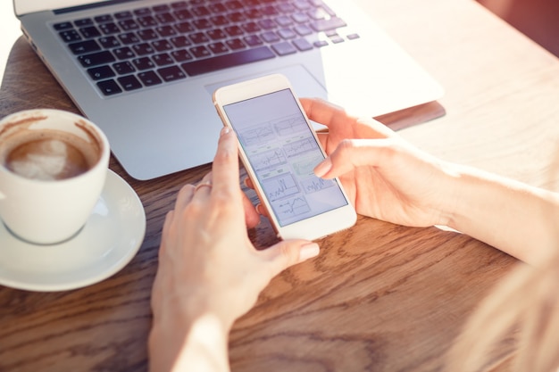 La ragazza nel caffè è in possesso di un telefono. il concetto di un posto di lavoro moderno.