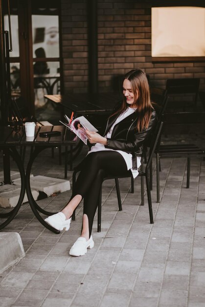 a girl in a cafe is sitting and reading a magazine