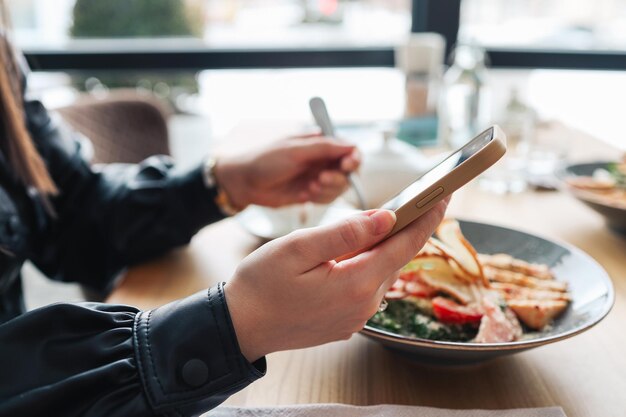 電話を使用して昼食時にカフェの女の子