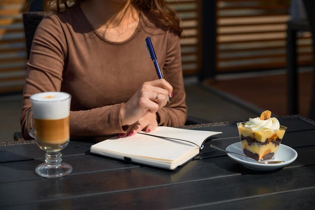 Foto una ragazza in un caffè scrive su un taccuino