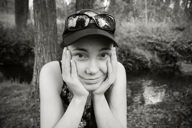 Girl in cap and sunglasses sitting with head in hands, black and white photo