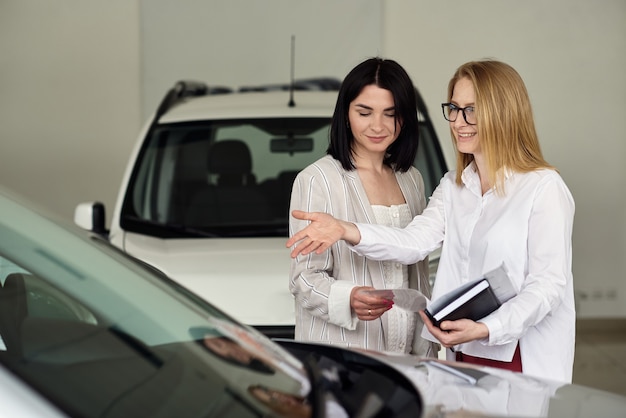 A girl in a car dealership buys a small city car.