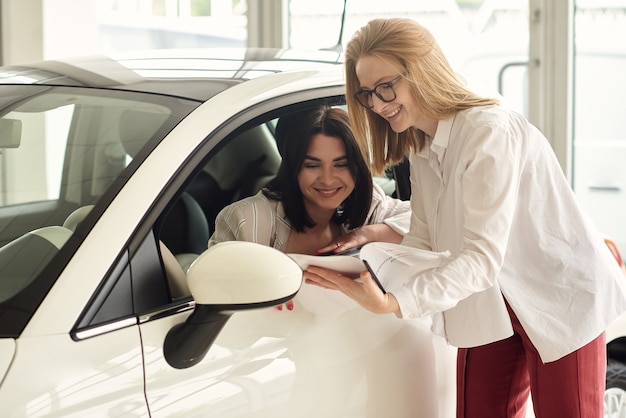 Una ragazza in una concessionaria di auto acquista una piccola city car.