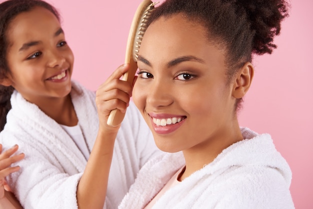 Girl carefully combing mother's hair.