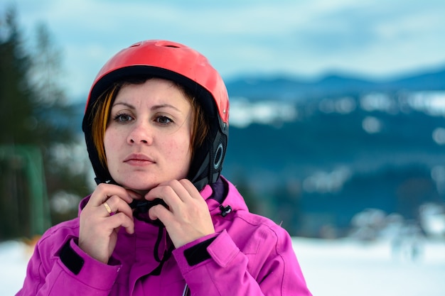 Photo girl in the carpathians in a purple jacket and red helmet.