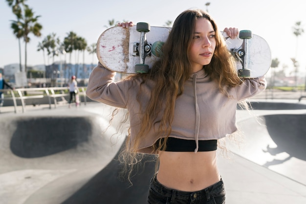 Girl carrying skateboard medium shot