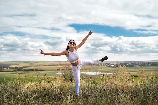 Girl in casual cloth in a rural green field goes in summer. lifestyle