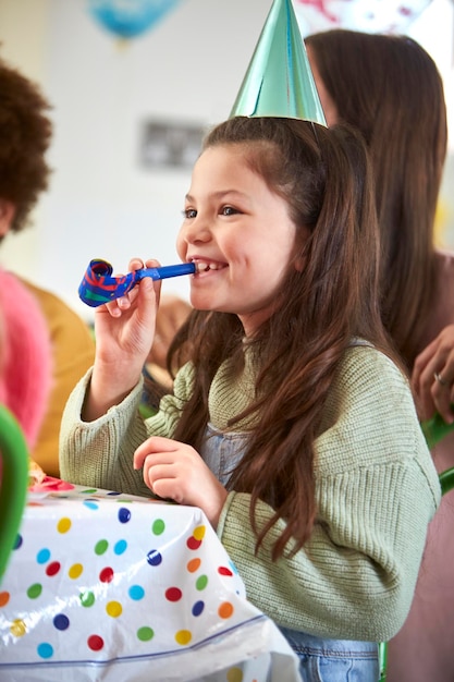 自宅で両親や友人とのパーティーでパーティーブロワーと誕生日を祝う女の子