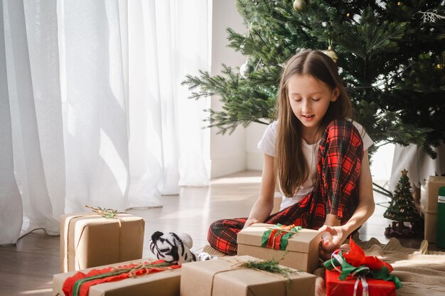 写真 家でクリスマスを祝う女の子がプレゼントを開封している