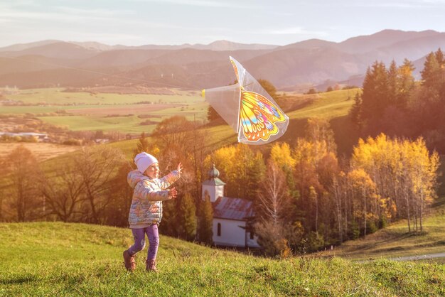Girl chasing a kite in a field at sunset