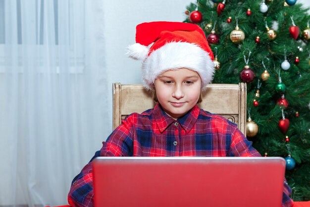 Girl chats on laptop in the background of Christmas tree