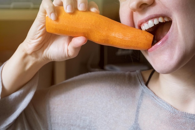 A girl chews a carrot