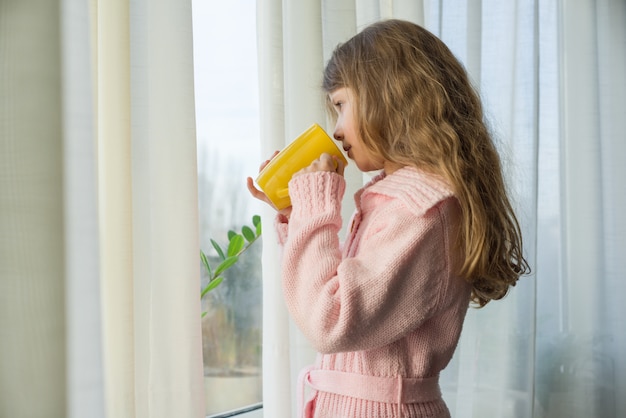 Girl child 7 years old blonde with cup of tea