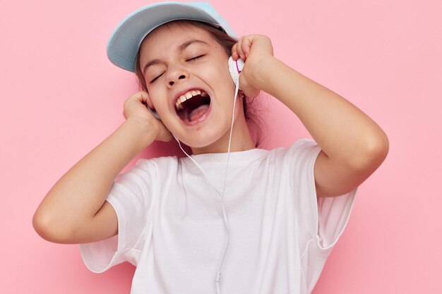 Girl child in headphones posing on a pink background