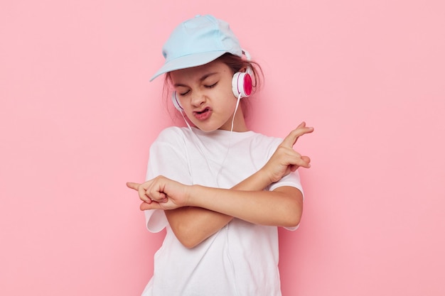 Girl child in headphones posing on a pink background