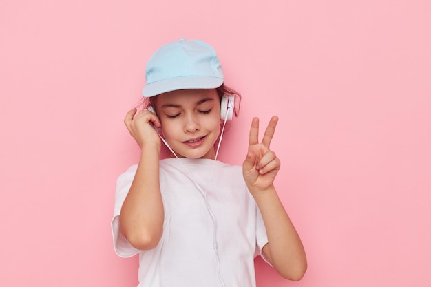 Girl child in headphones posing on a pink background