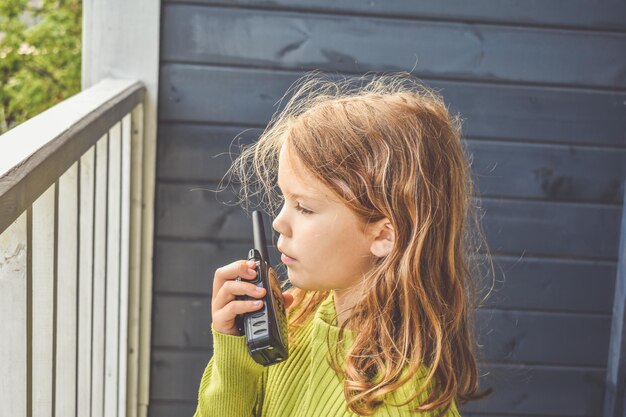 The girl child is talking on the radio on a sunny summer day