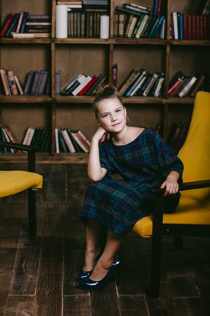 Girl child in the library with books in a strict fashion is engaged in education and training