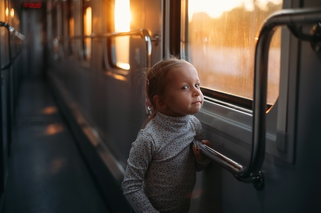 Girl child looking though train window on sunset