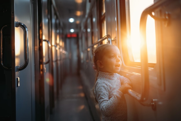 夕焼けの電車の窓から見ている女児