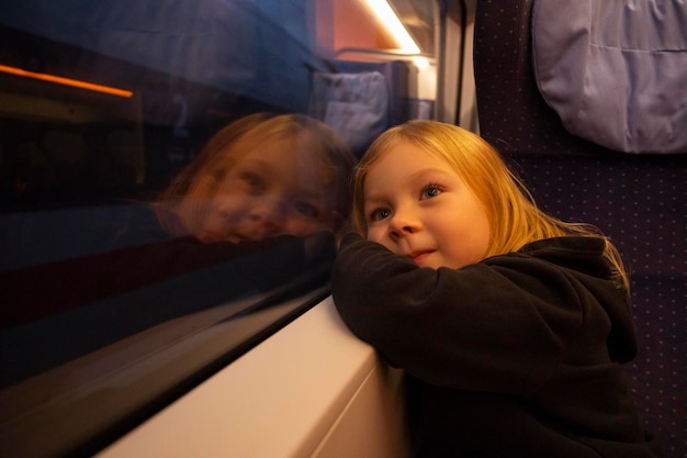 Photo girl child looks out the window sitting in the train