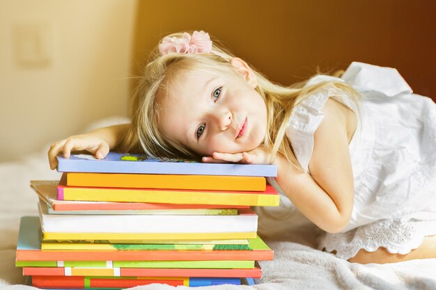 Girl child lying on the bed with books