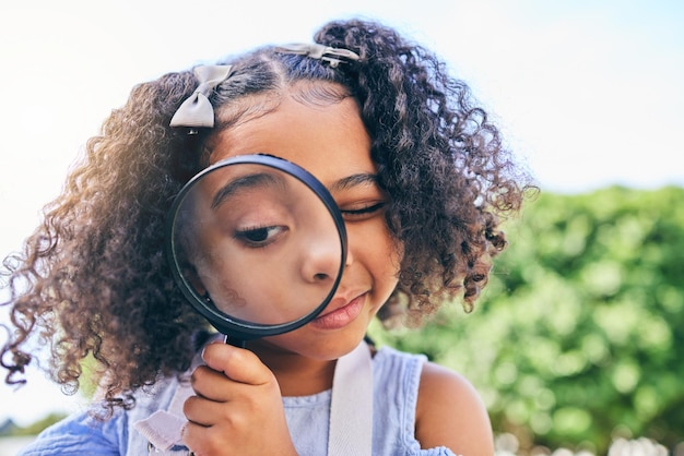 写真 女の子の子供の虫眼鏡と科学研究や屋外の庭の裏庭や公園での検査若い女性の子供のレンズと自然検索のためのズーム、夏の植物の葉や成長の確認