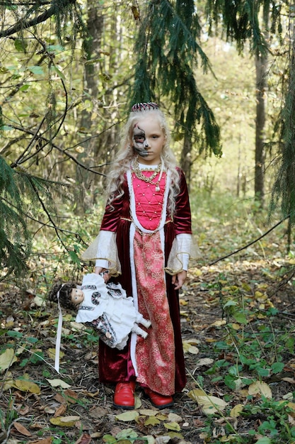 Girl child posing in the forest in a medieval dress in the image of a dead princess