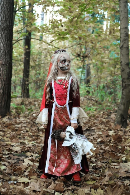 Girl child posing in the forest in a medieval dress in the image of a dead princess