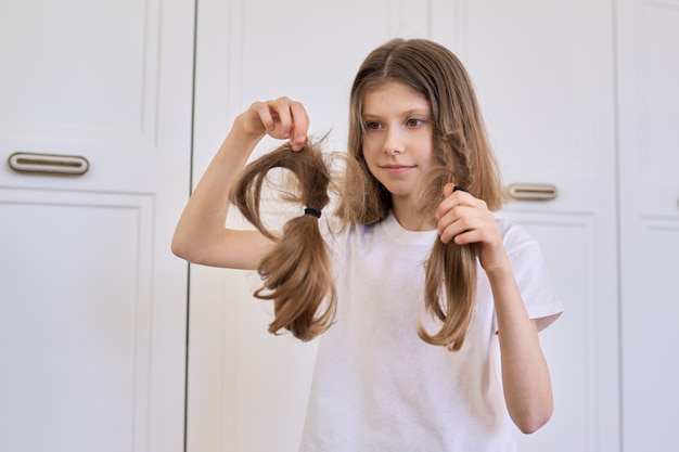 Girl child shows trimmed hair, hairdresser at home, copy space.