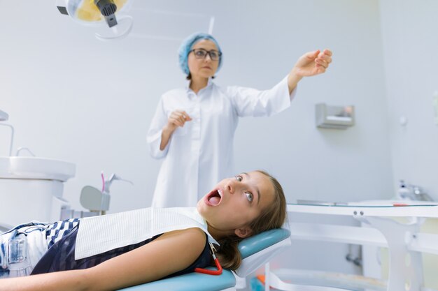 Girl child sitting in dental chair treating teeth
