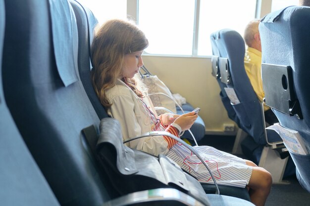 Girl child using smartphone while sitting inside ferry