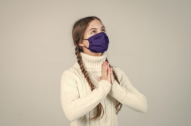 Girl child wearing respirator mask to protect from coronavirus pray