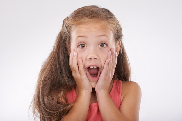 Girl child with face and surprise shock in studio with reaction or facial expression to drama and gossip Wow emoji and fear with story info or announcement with portrait on white background