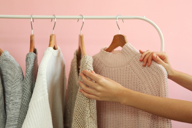 Girl chooses a warm sweater from the wardrobe of the hanger