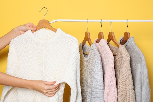 소녀는 옷걸이의 옷장에서 따뜻한 스웨터를 선택합니다
