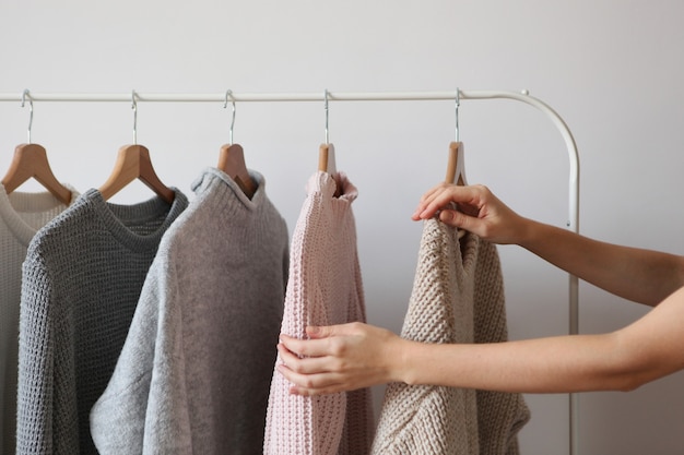 Girl chooses a warm sweater from the wardrobe of the hanger