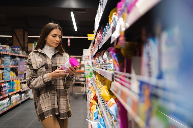 Girl chooses washing powder in the household chemicals department in the store