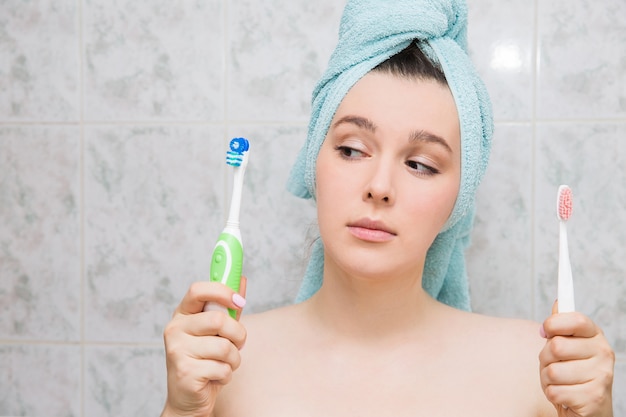 Photo girl choosing an electric or ordinary toothbrush.