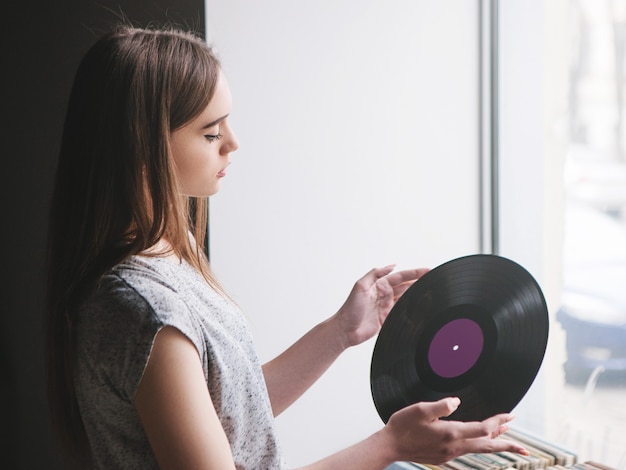 Ragazza che sceglie i dischi in vinile retrò nel negozio di musica. stile hipster moderno, giovane donna melomane