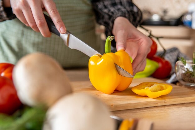 Ragazza che taglia il peperone giallo, cucina casalinga, fondo della cucina