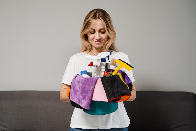 Girl cleaner is holding bucket with detergent and microfiber rags for house cleaning Professional domestic cleaning service