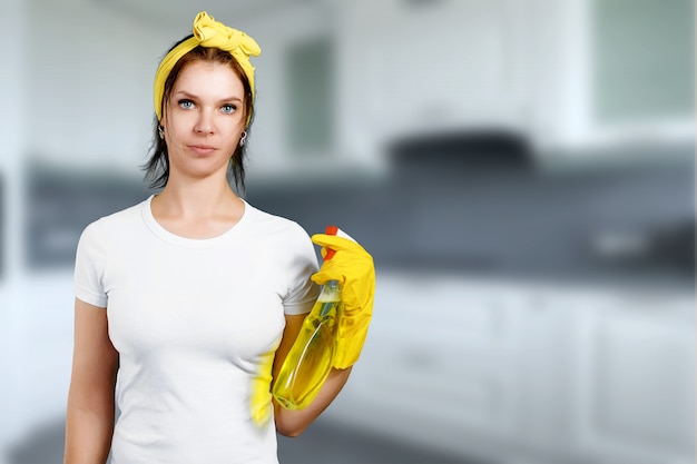 A girl a cleaning lady with a cleanser wearing gloves and a rag