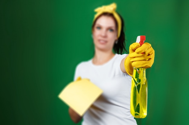 A girl a cleaning lady with a cleanser wearing gloves and a rag