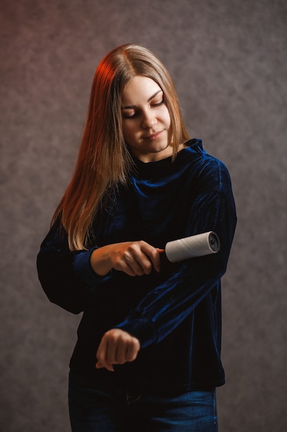 Girl cleans a sweater with a special roller with adhesive tape