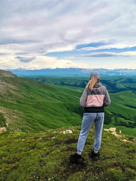 A girl on the cliff of the plateau against the background of Mount Elbrus Bermamyt