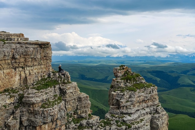 A girl on the cliff of the plateau against the background of Mount Elbrus Bermamyt